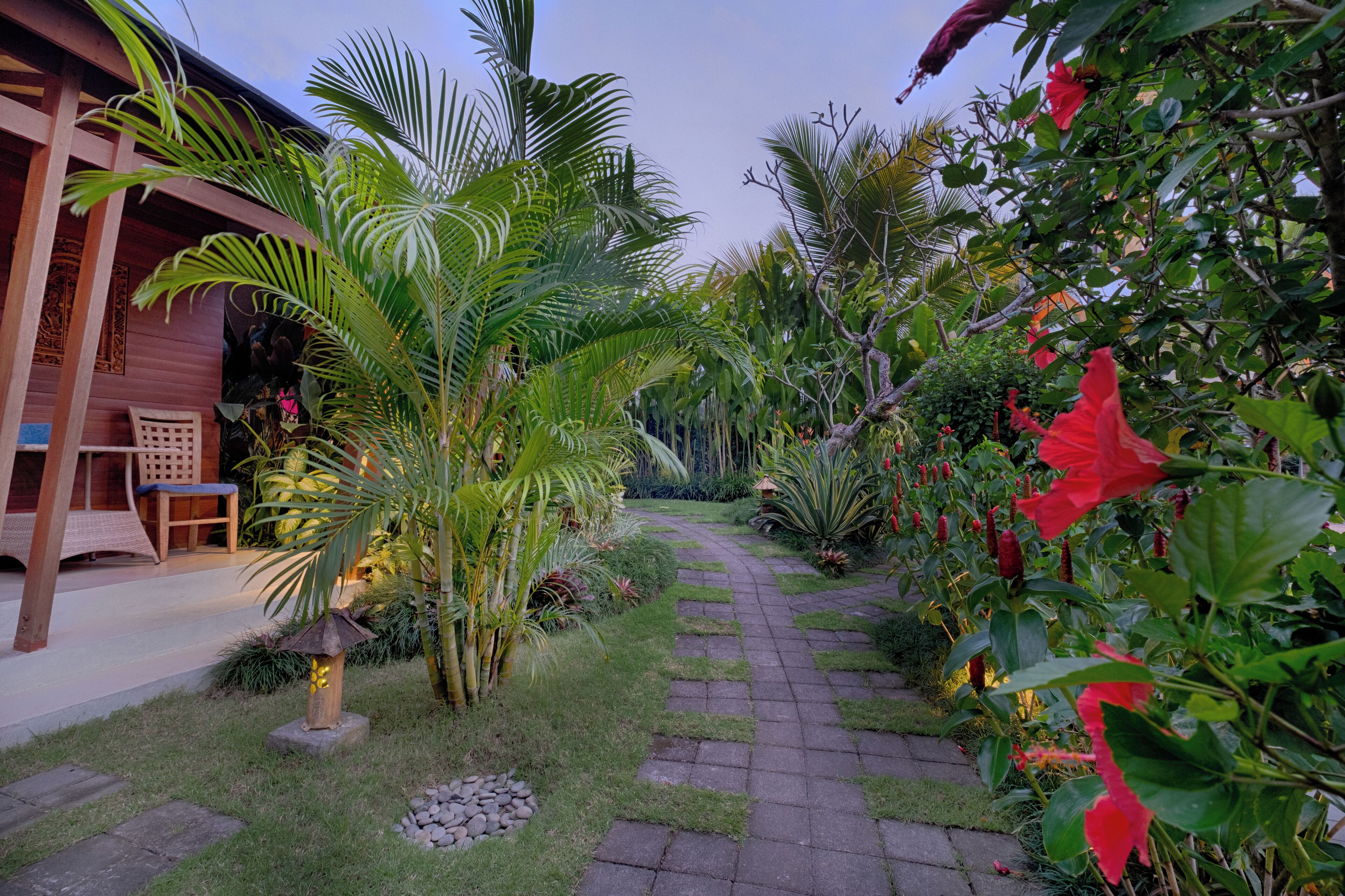 A garden pathway leading to a wooden building with a seating area.