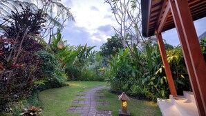 A garden pathway leading to a building with a wooden structure. - Villa Tegal Tis Ubud (Ubud)