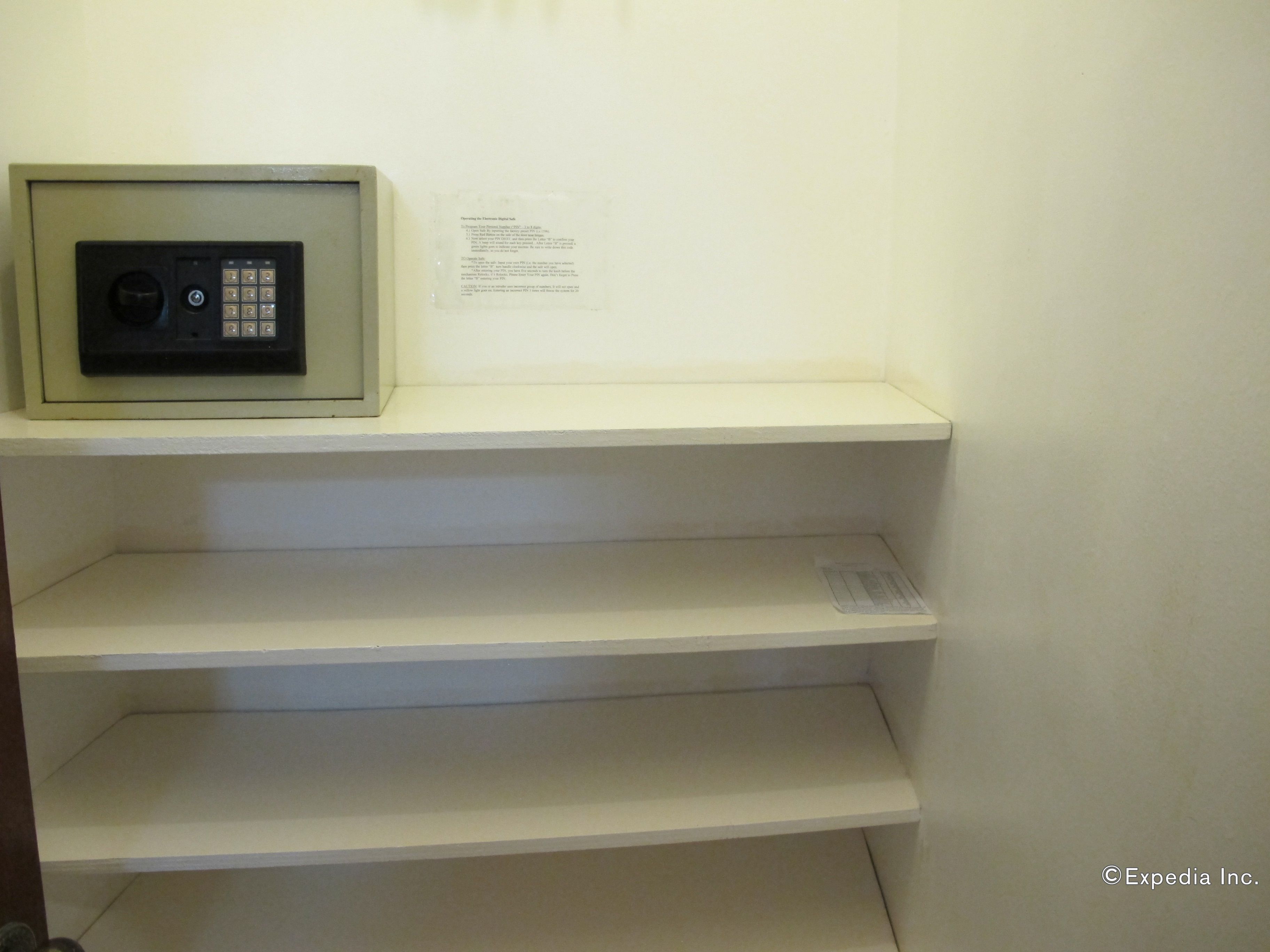 Una habitación con una caja de seguridad pequeña en un estante y un aviso en la pared.