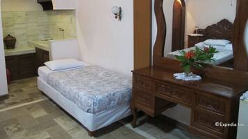 A bedroom with a bed, a dresser, a mirror, and a small table with a vase.