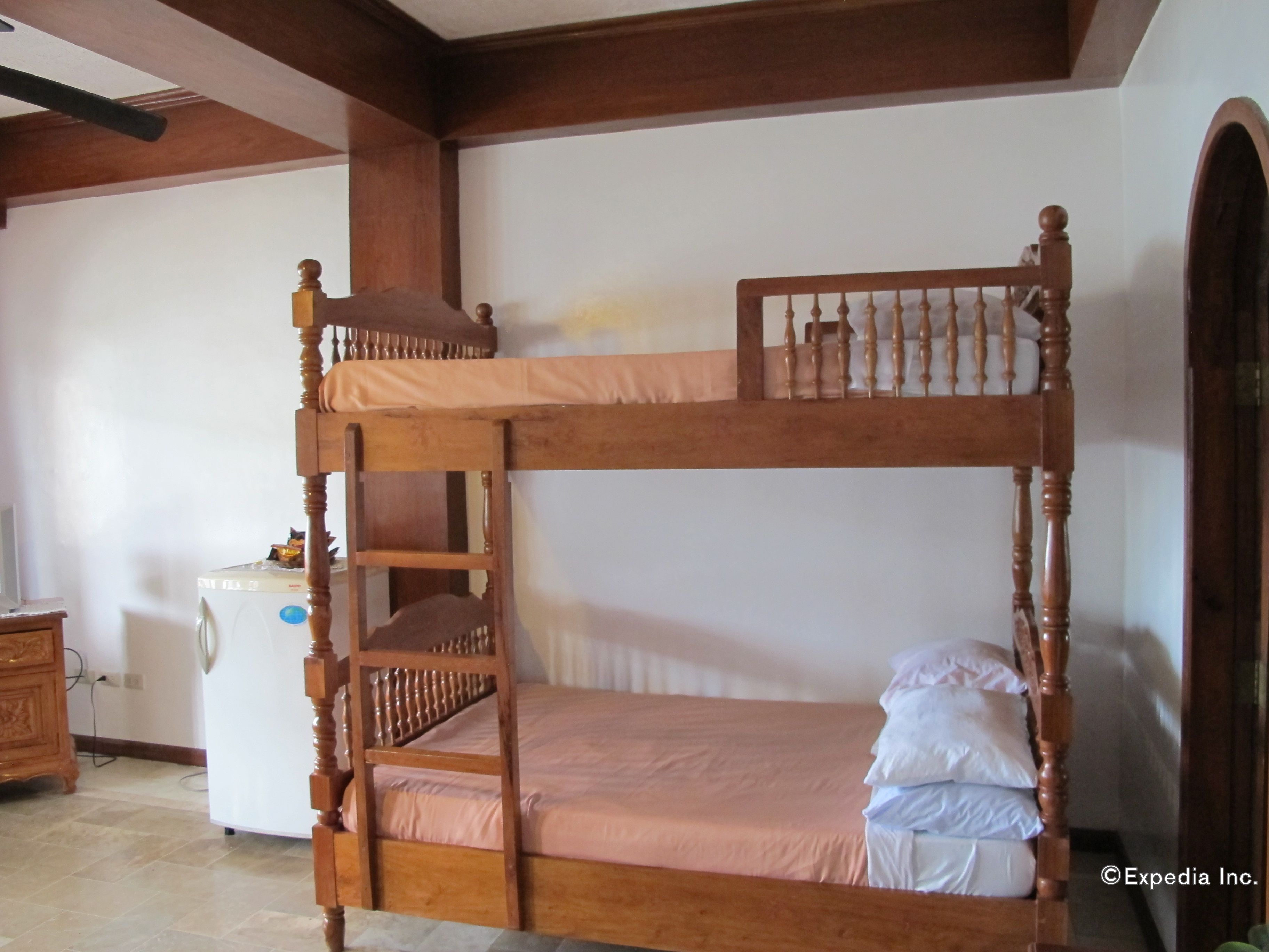 A bunk bed with a wooden ladder, a small bedside table, and a white wall in the background.
