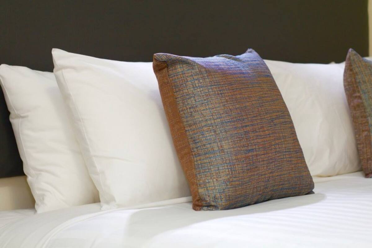 A bed with white pillows and a single patterned pillow.