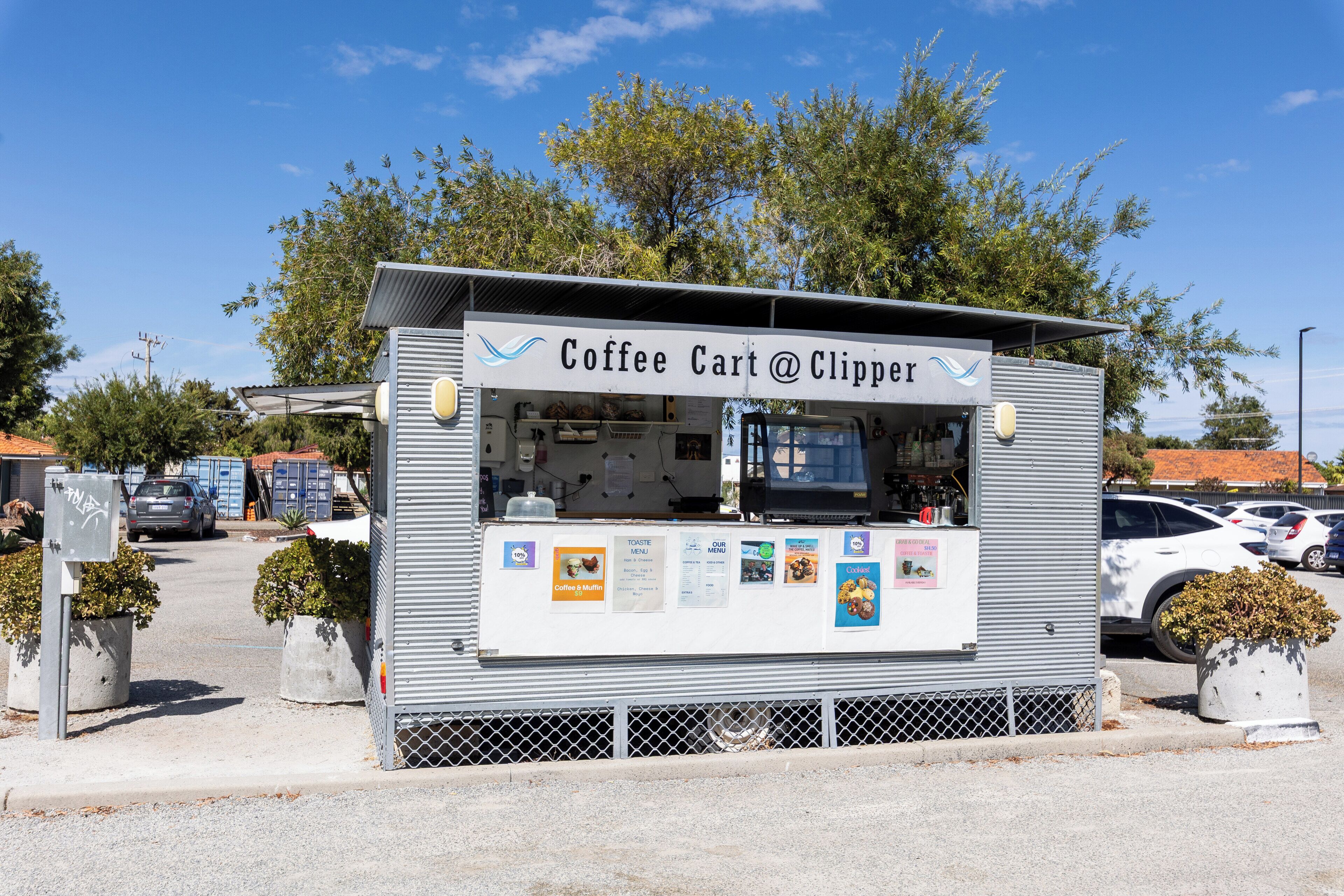 A mobile coffee cart with a menu board and a sign that reads 'Coffee Cart @ Clipper'.