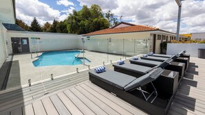 Ein Poolbereich auf dem Dach mit Liegestühlen und einem überdachten Pool.