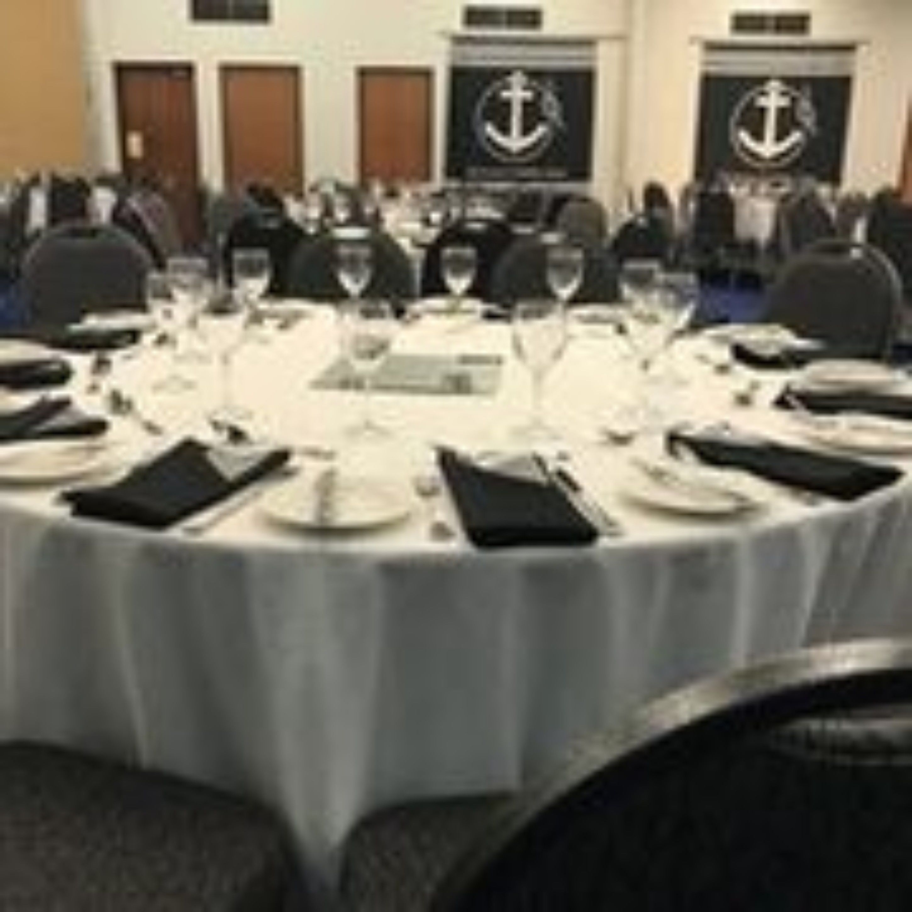 A conference room with round tables set for a meeting, equipped with nameplates, glasses, and cutlery.
