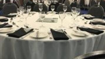 A conference room with round tables set for a meeting, equipped with nameplates, glasses, and cutlery.