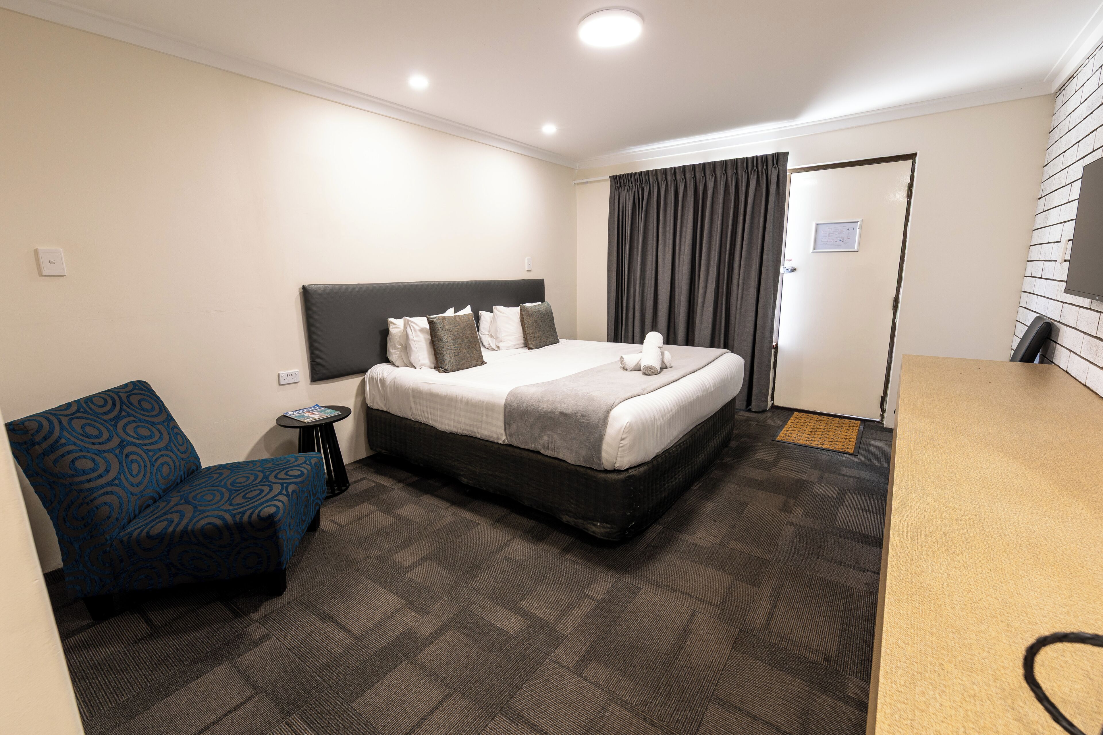 Une chambre d’hôtel avec un lit, une chaise, une petite table et une porte.