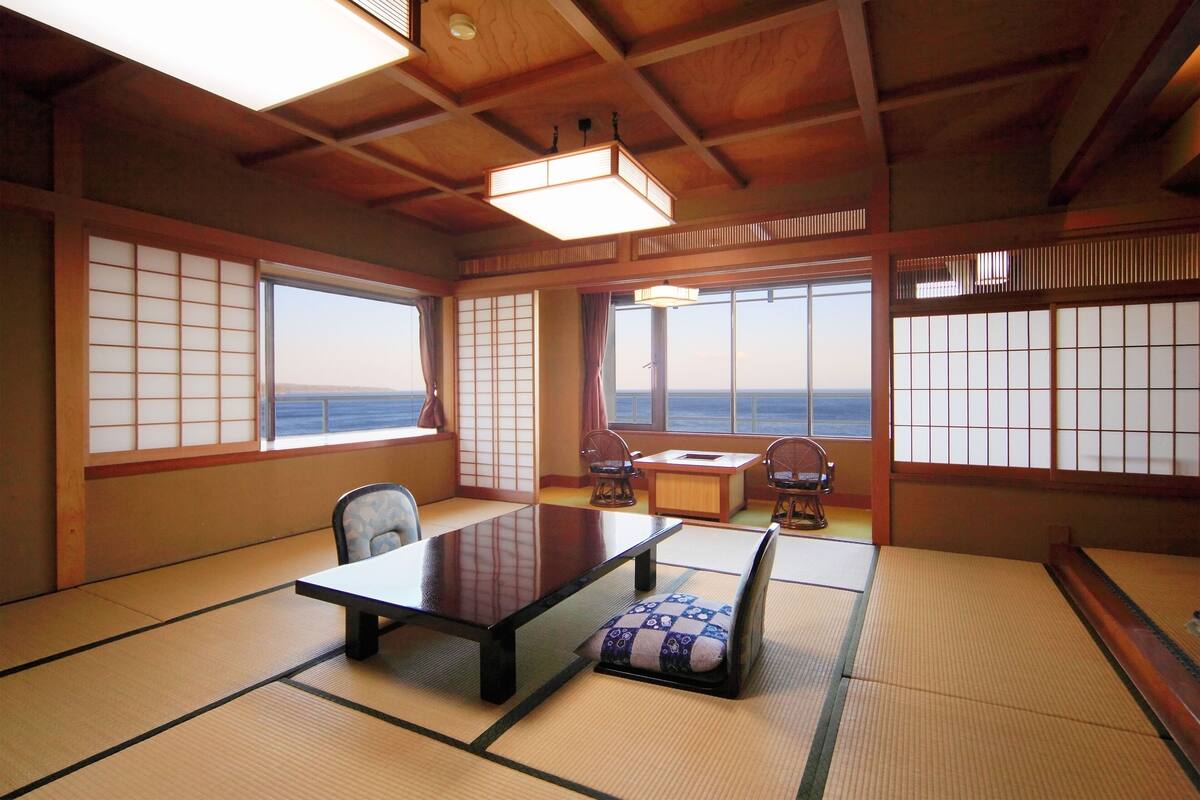 Une pièce de style japonais traditionnel, avec un sol recouvert de tatamis, une table basse et une vue sur la mer.