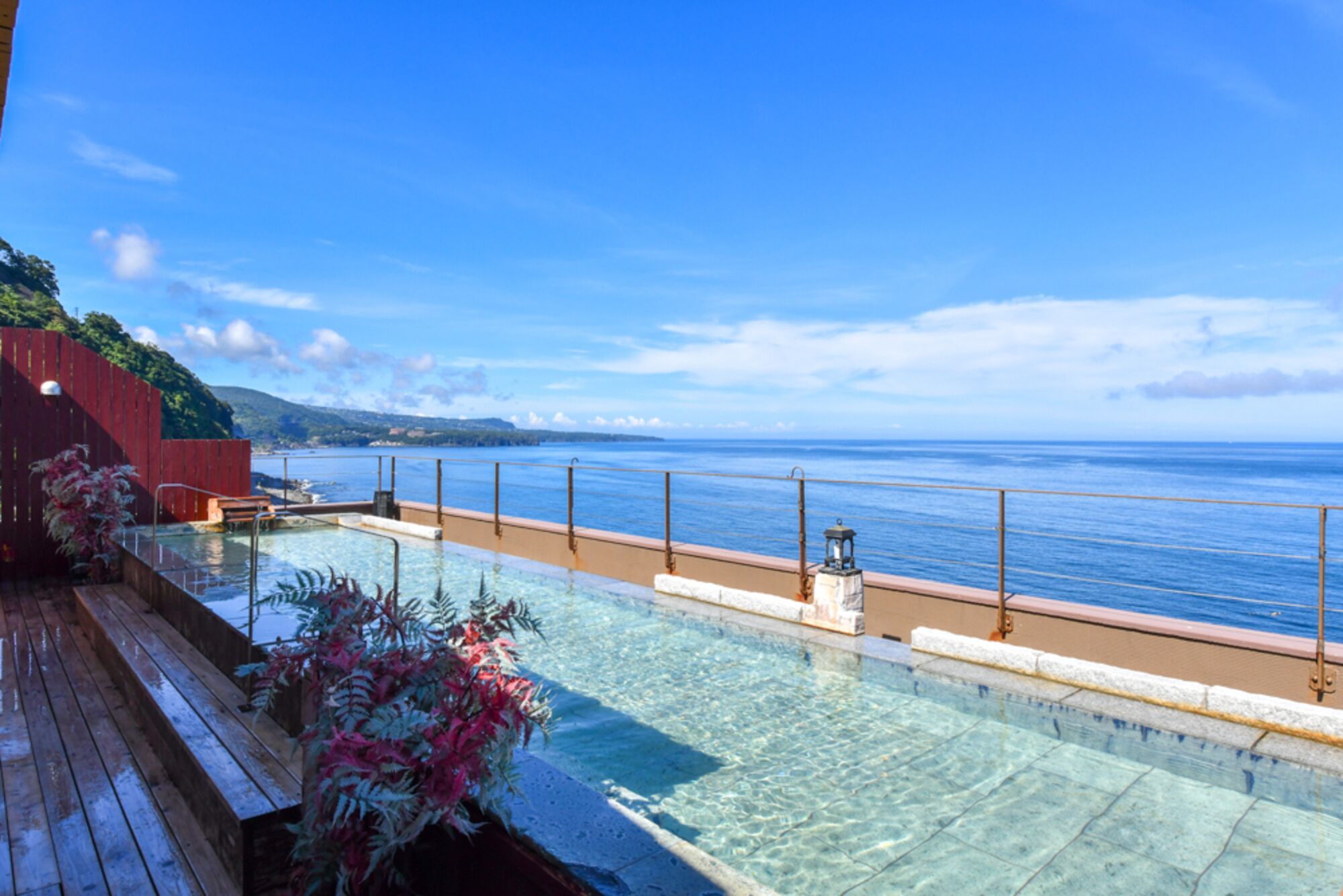Una piscina cristalina con muelle de madera y vista al mar.