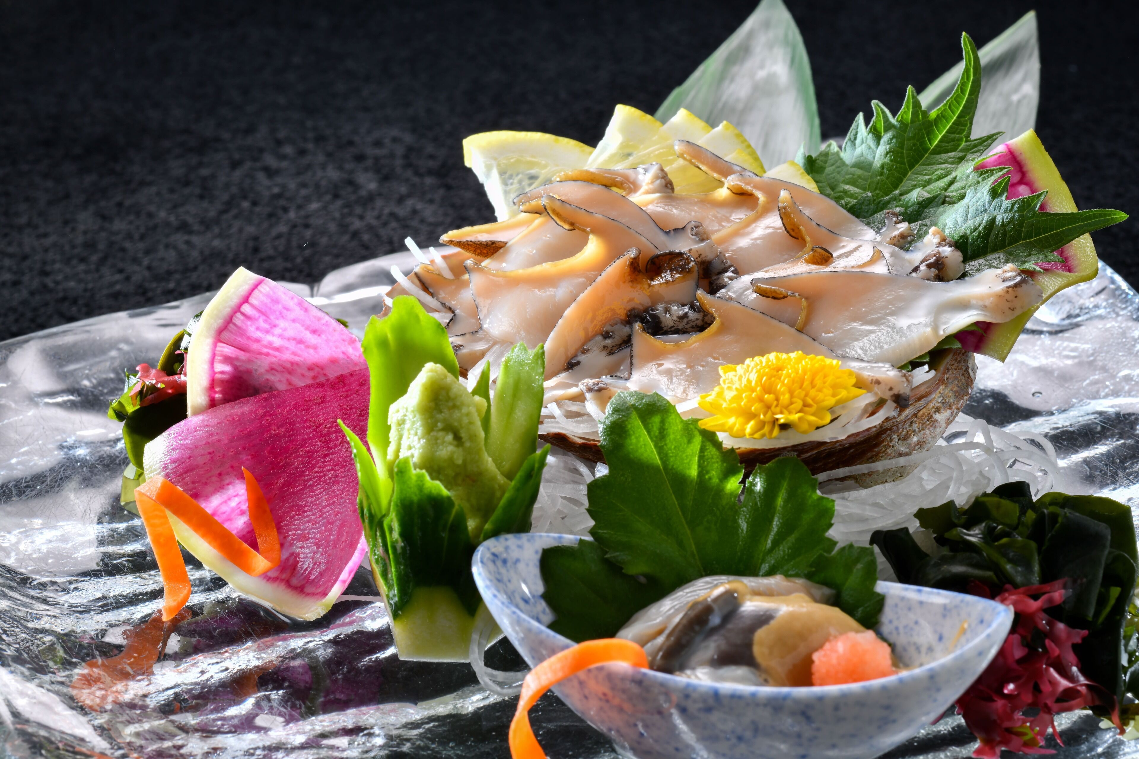 A seafood dish with various garnishes on a clear glass plate.