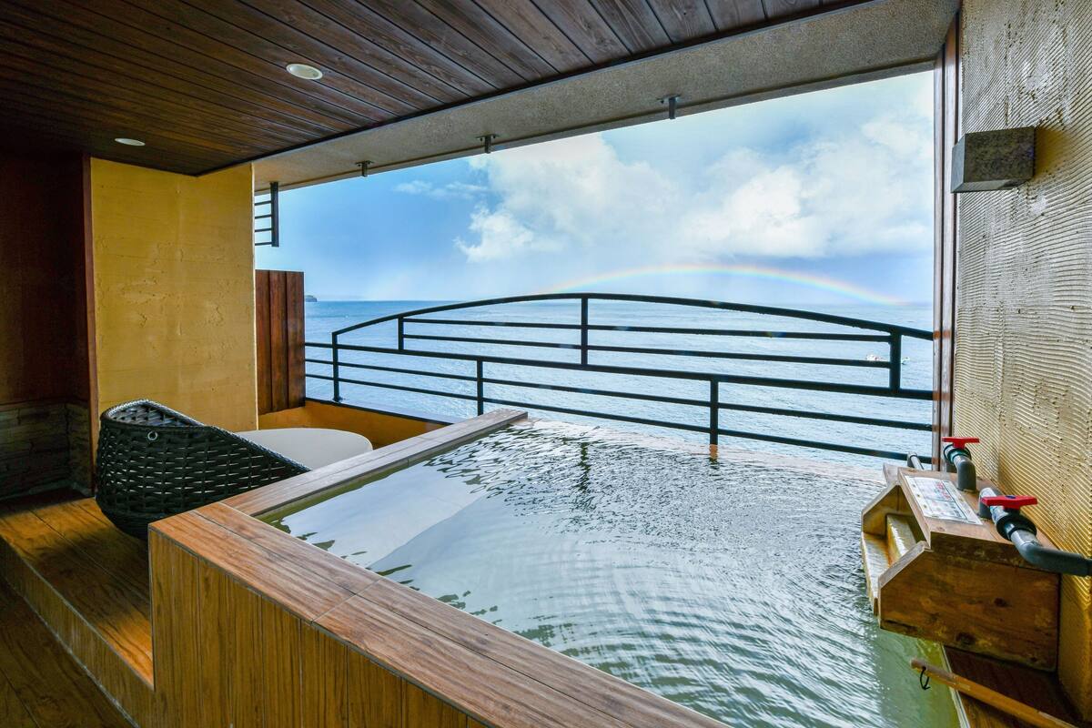 Un espace spa doté d’une terrasse en bois, d’un jacuzzi et offrant une vue sur l’océan.