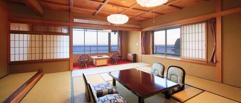 A traditional Japanese room with tatami flooring, a low table, and a view of the sea.