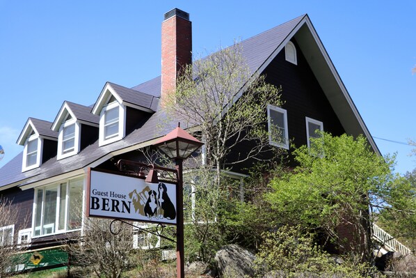 A two-story house with a sign reading "Guest House BERN" and a chimney.