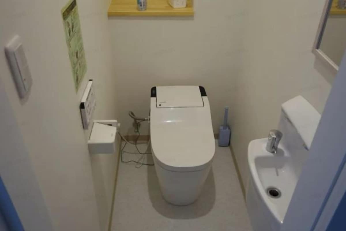A small bathroom with a toilet, sink, and a shelf above the toilet.