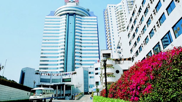 A modern hotel with a curved facade, multiple floors, and a prominent entrance.