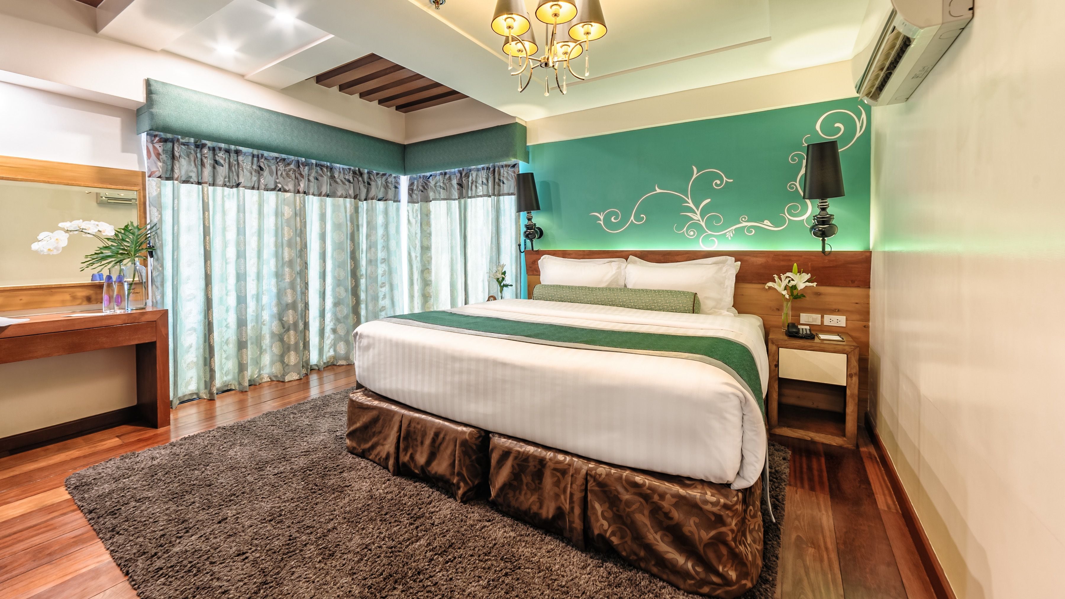 A modern bedroom with a large bed, wooden headboard, and a green accent wall.