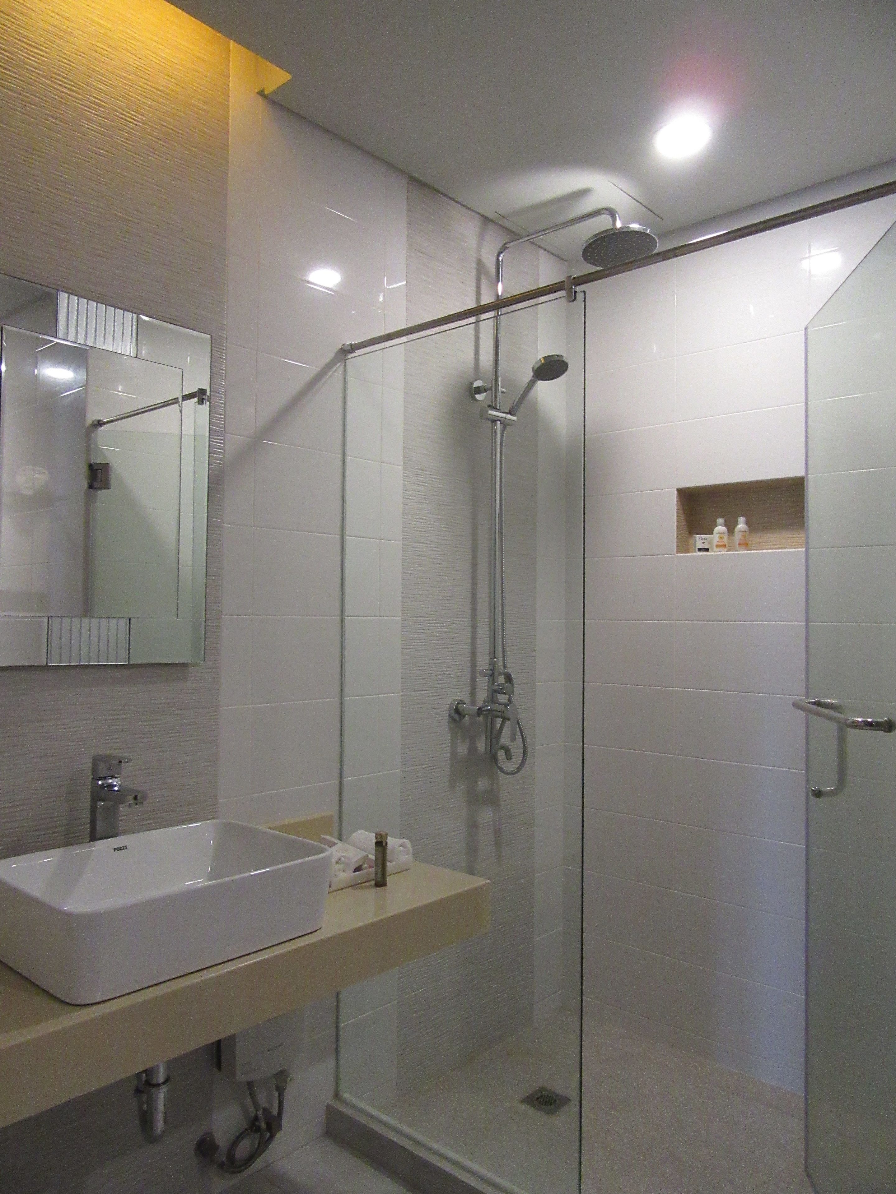 A modern bathroom with a glass-enclosed shower, a white sink, and a mirror above it.