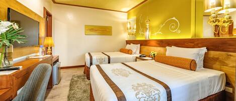 A hotel room with two beds, a desk, a chair, a TV, and a mirror.