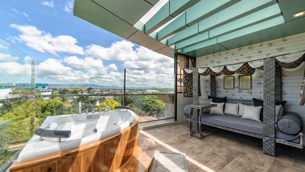 Un balcón con un jacuzzi, un sofá y vistas a la ciudad.