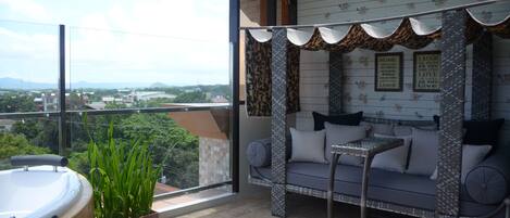 A balcony with a sofa, a small table, and a hot tub.