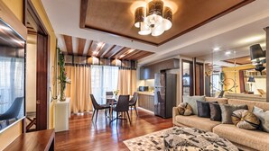 Una sala de estar moderna con piso de madera, un juego de sofá, un comedor con sillas y una zona de cocina con refrigerador.