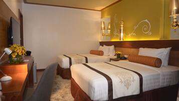A hotel room with two beds, a desk, a chair, and a TV.