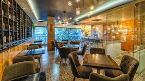 Un restaurante moderno con barra, mesas y vistas a árboles a través de amplios ventanales.