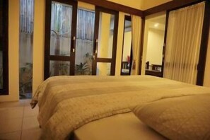 A bedroom with a bed, curtains, and a view of the outdoors.