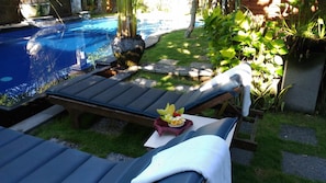 A poolside lounge area with a small table and two lounge chairs.