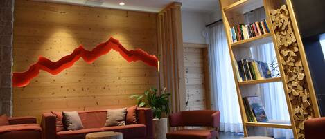 Een modern interieur met een houten wand, een golvend rode lamp, een rode bank, een houten boekenkast en een potplant.