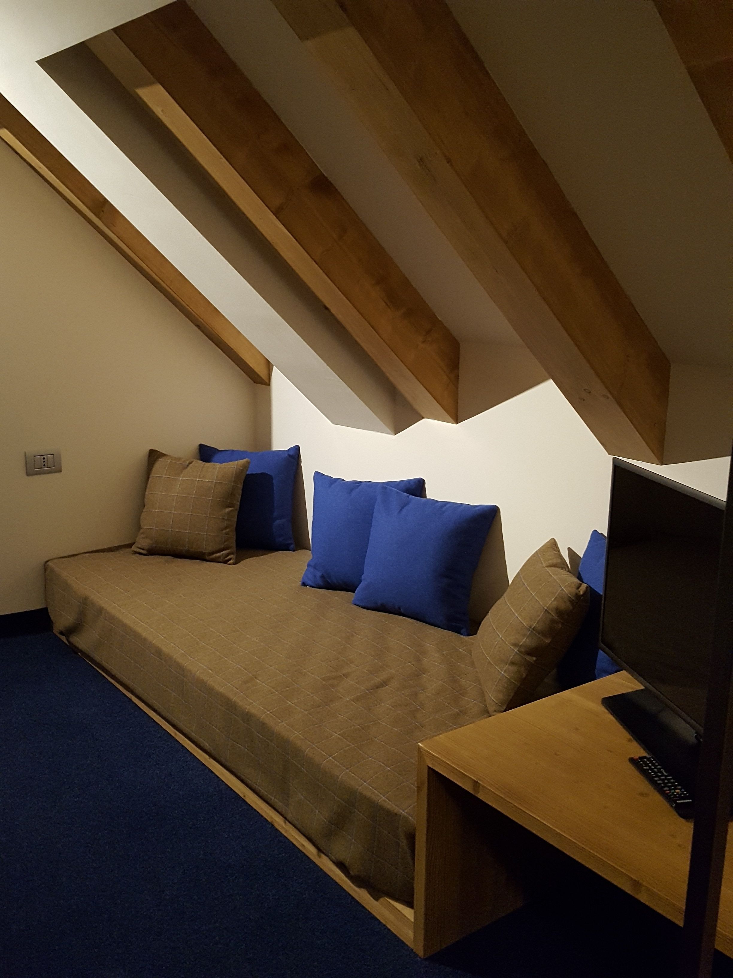A small, cozy room with a bed, a TV, and a wooden desk.