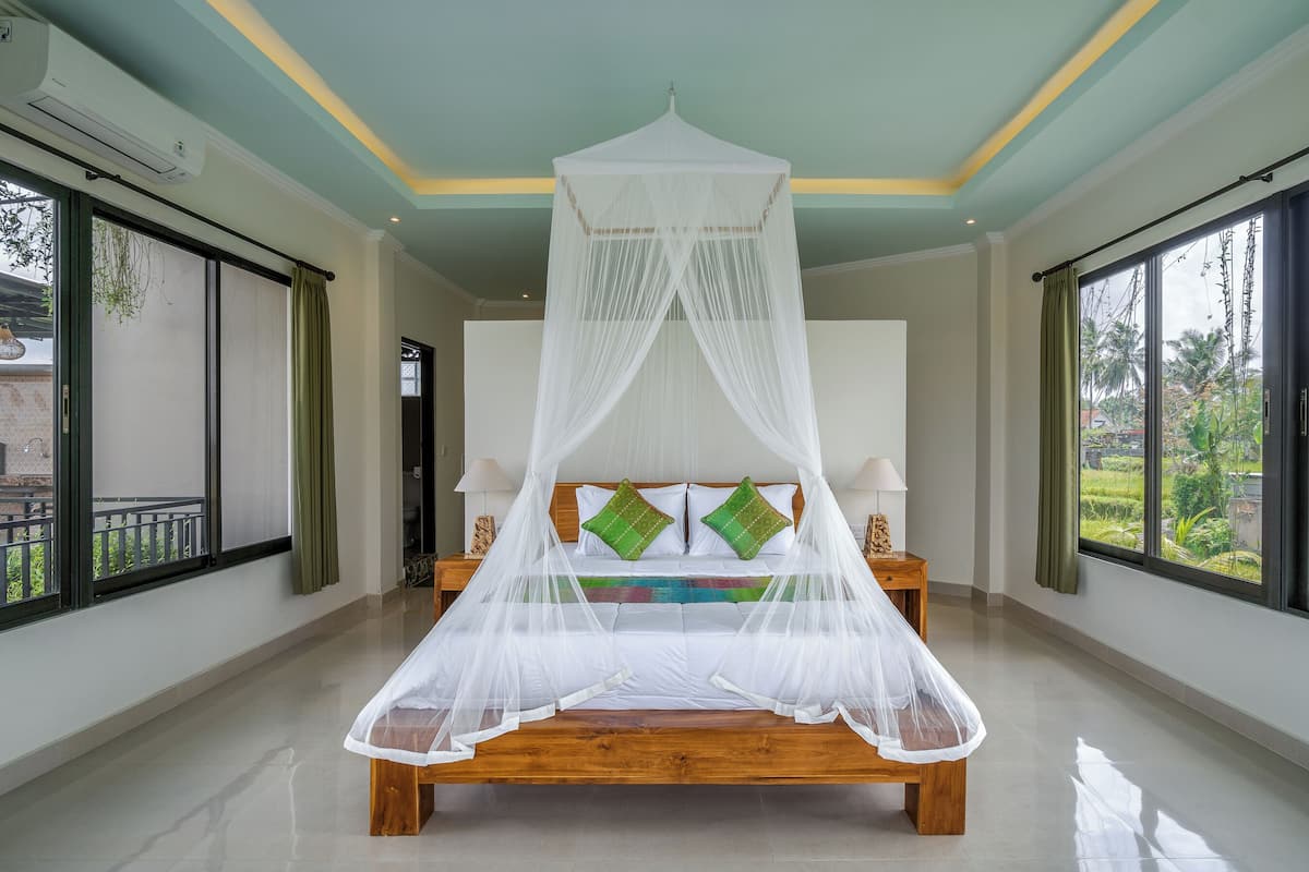 A spacious bedroom with a large bed, a canopy, and a view of the outdoors.
