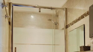 A modern bathroom with a glass-enclosed shower, a white sink, and a toilet.