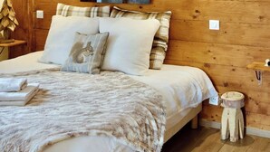 A cozy bedroom with a wooden ceiling, a large bed with multiple pillows, and a painting on the wall.