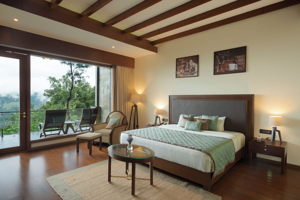 Ein geräumiges Schlafzimmer mit einem großen Bett, einem Glastisch und einem Balkon mit Sitzgelegenheiten.