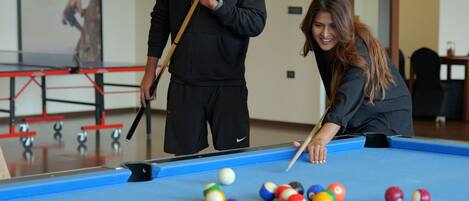 A pool table with balls, a person aiming a cue, and a framed picture on the wall.
