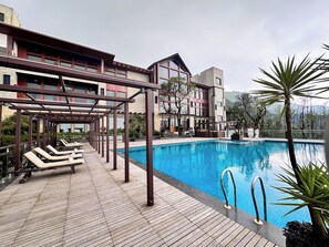 A pool area with sun loungers and a clear blue pool.