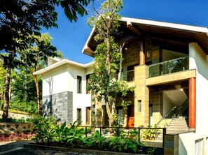 A modern two-story house with a stone facade, large windows, and a balcony.