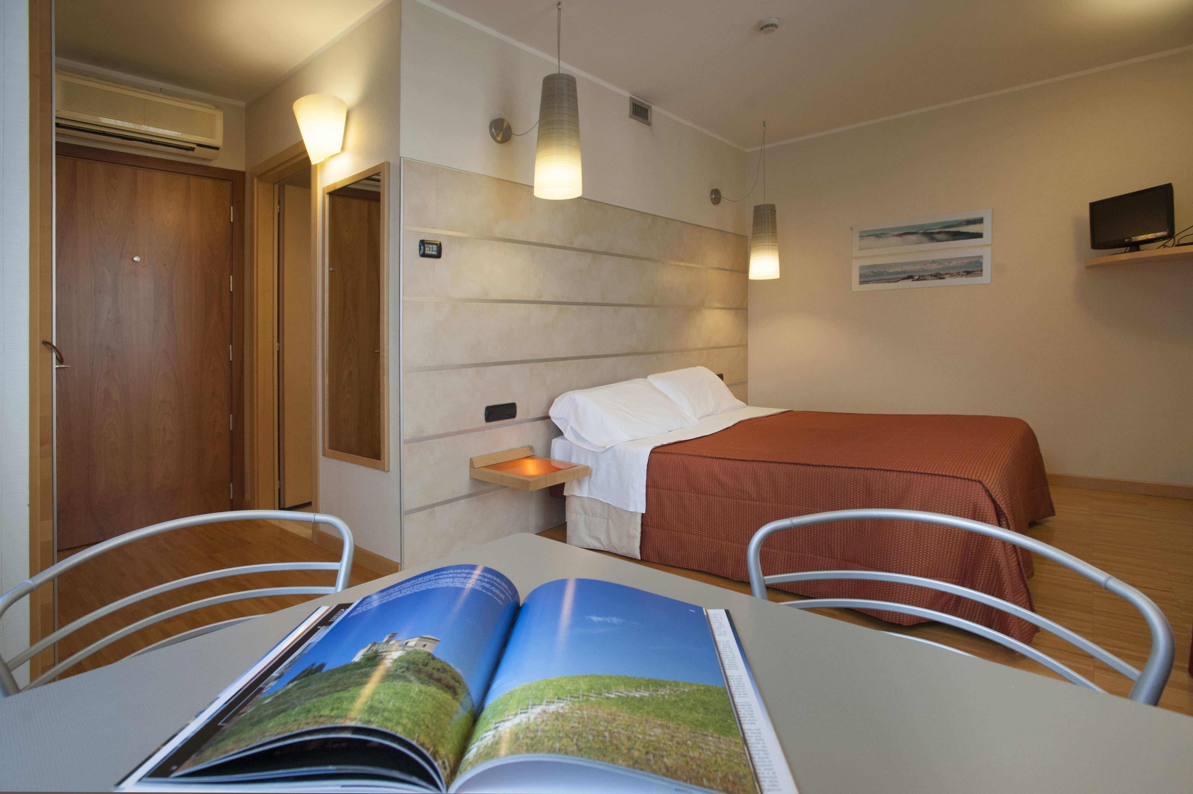 Une chambre d’hôtel avec un lit, une table de chevet et un magazine posé sur la table.