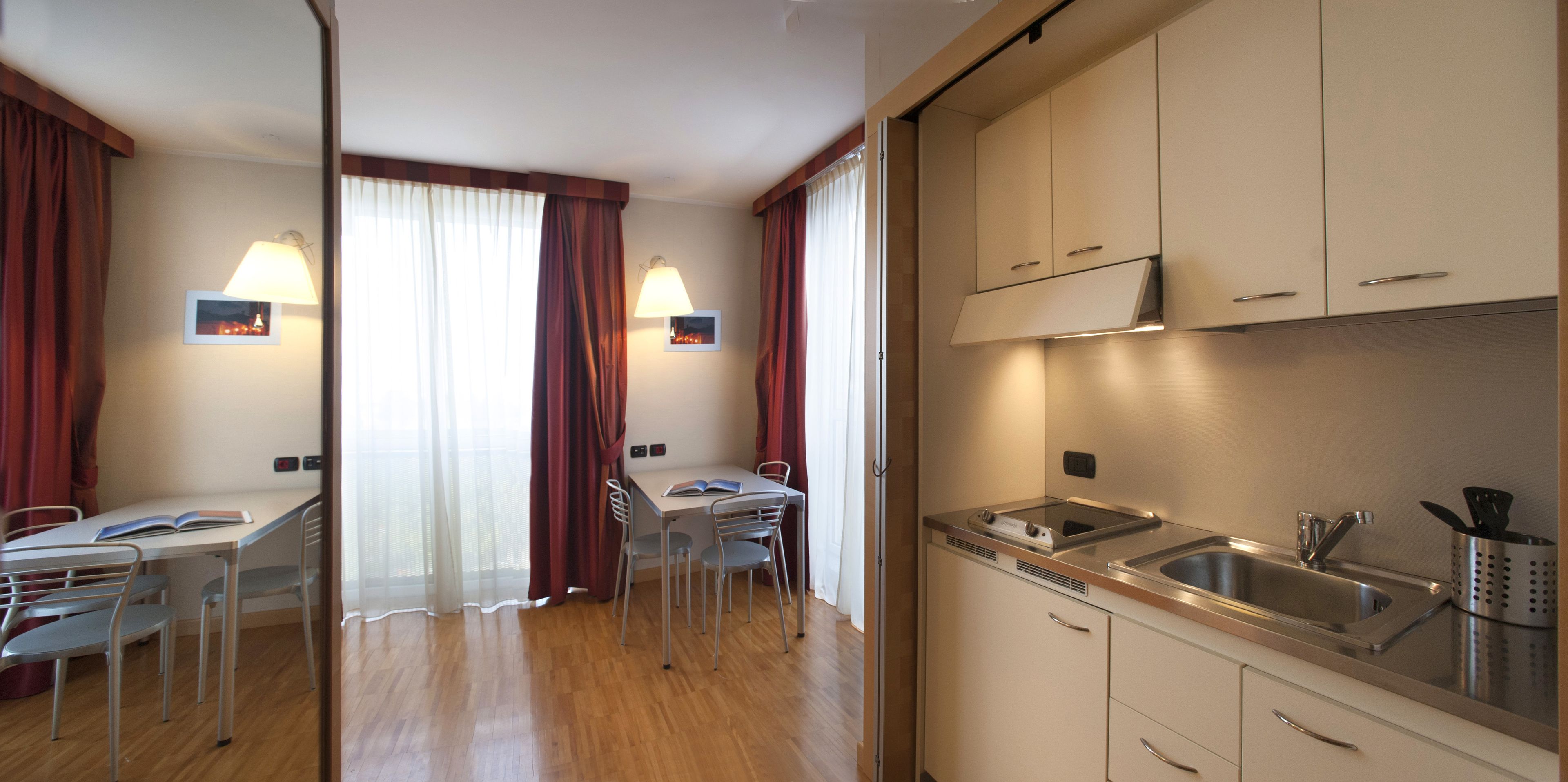 Cocina compacta con comedor, que incluye un lavamanos, estufa y sillas.