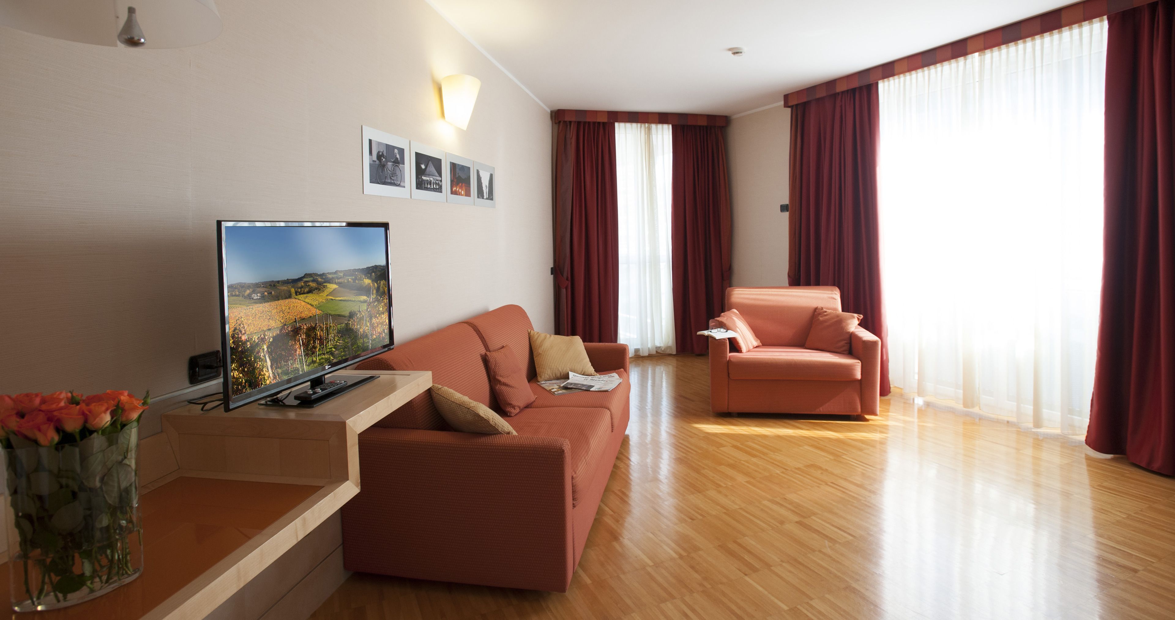 A modern living room with a flat-screen TV, a sofa, a chair, and a wooden coffee table.