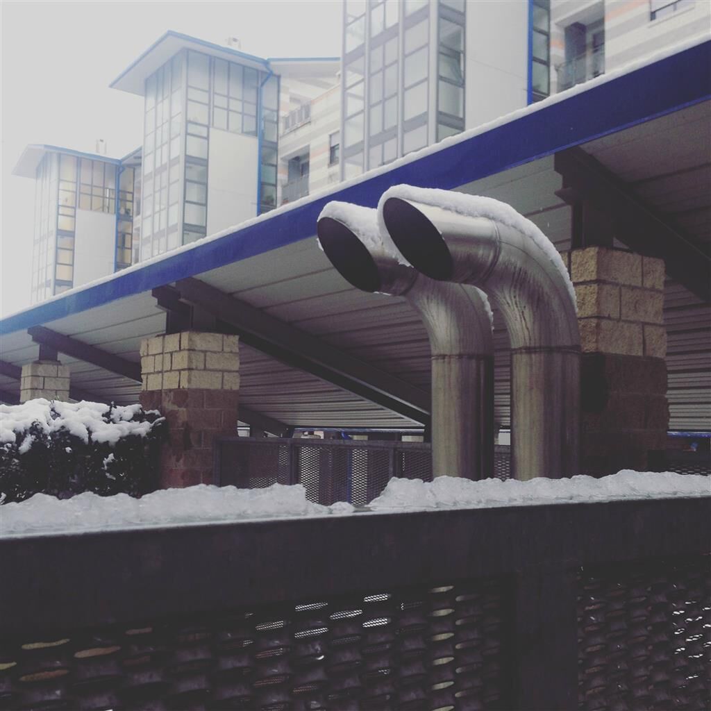 A building with a covered walkway and large metal pipes.