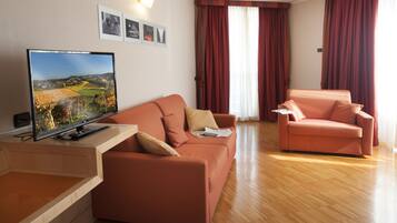 A modern living room with a flat-screen TV, two sofas, and a wooden coffee table.
