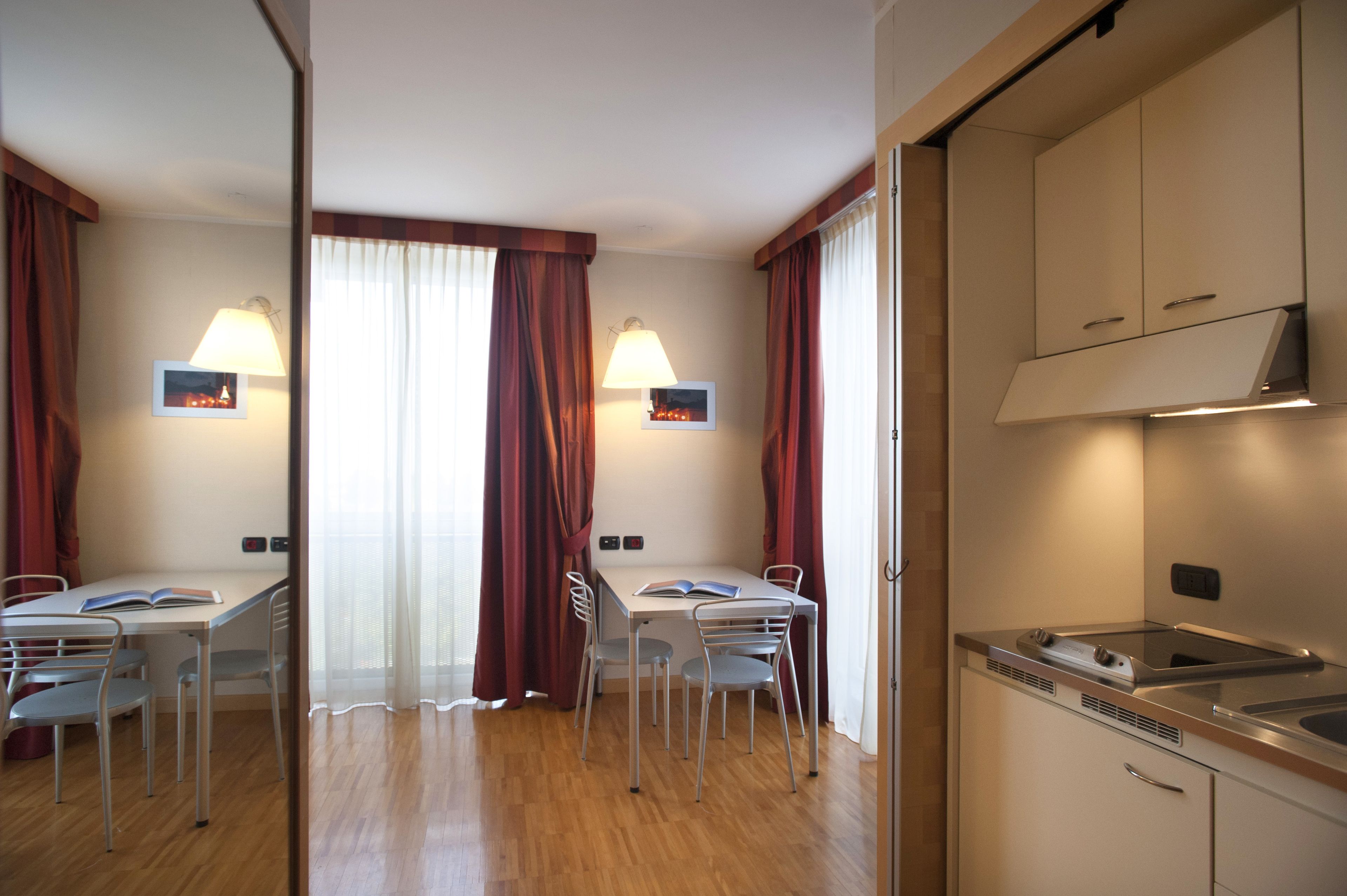 A modern kitchen with stainless steel appliances, a dining area with a table and chairs, and a large window with curtains.