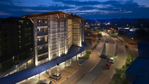 A modern hotel with a glass facade, a covered entrance, and a parking area. - AlbaResidence masera26 (Alba)