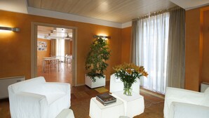 A modern hotel lobby with white furniture, a potted plant, and a vase of flowers. - AlbaResidence masera26 (Alba)