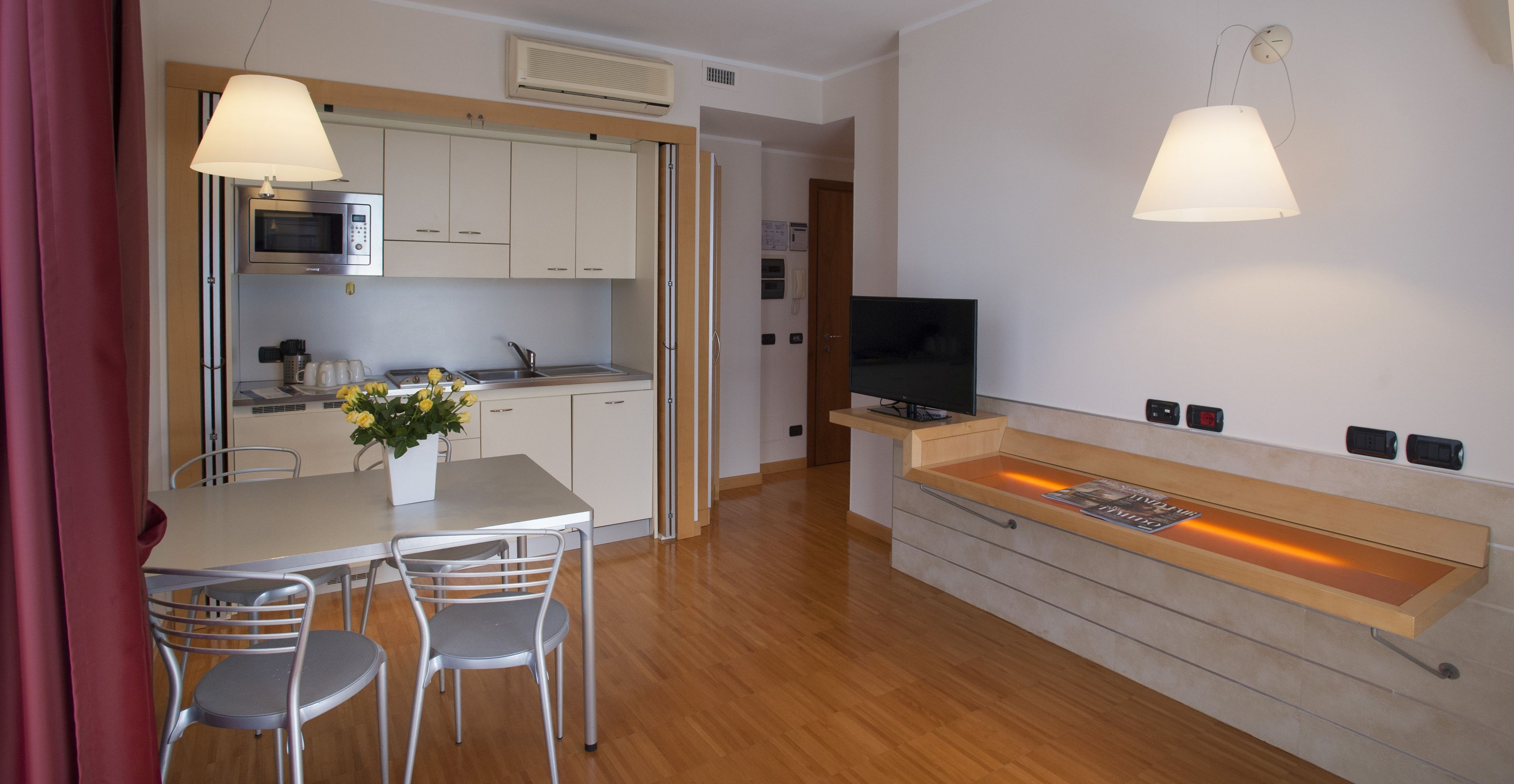 Een moderne keuken met een magnetron, spoelbak en een eethoek met stoelen.