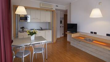 Een moderne keuken met een magnetron, spoelbak en een eethoek met stoelen.