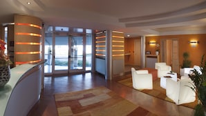 A modern hotel lobby with a reception desk, seating area, and large glass doors leading outside. - AlbaResidence masera26 (Alba)