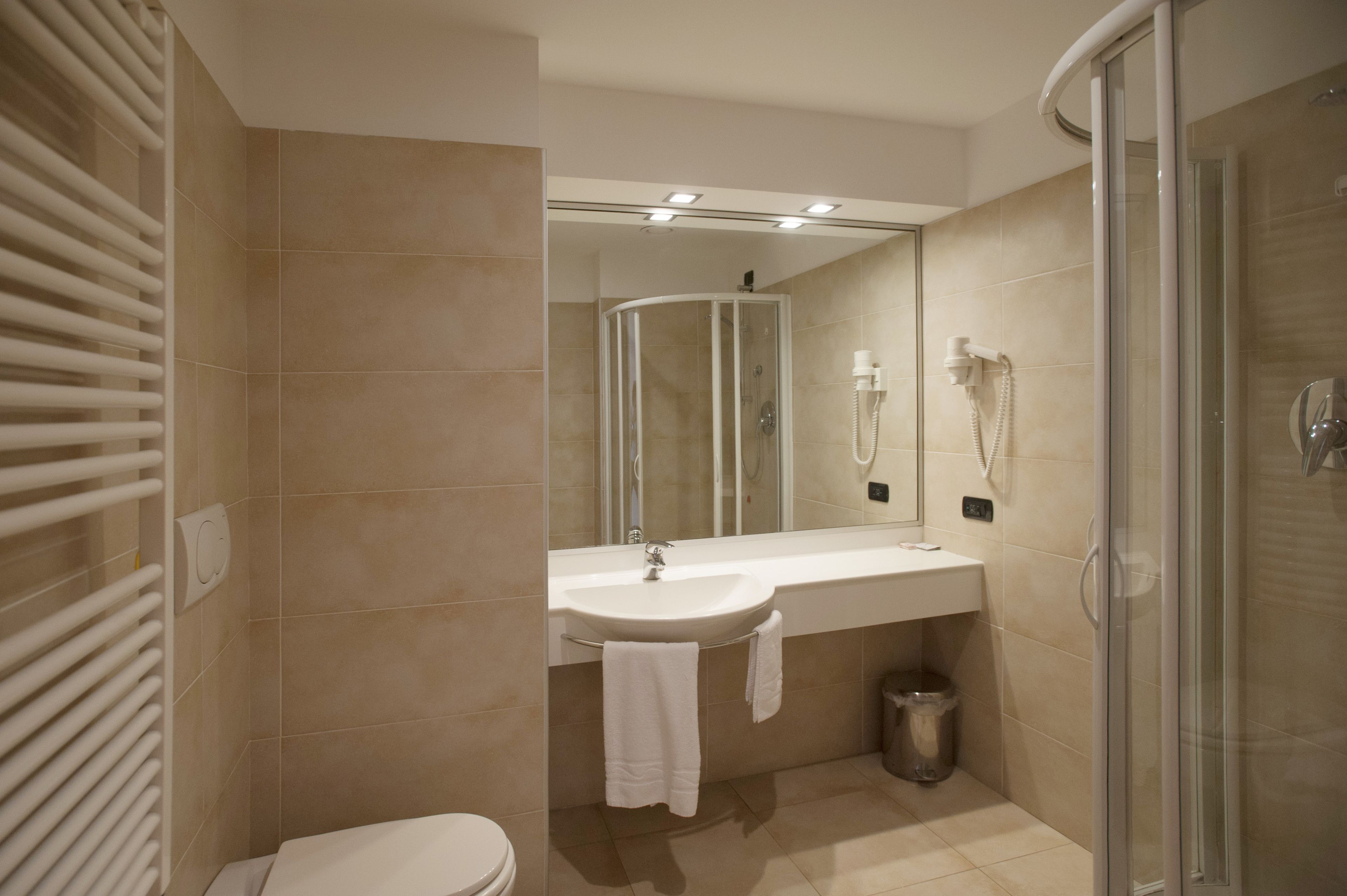 A modern bathroom with a glass-enclosed shower, a white sink, and a toilet.